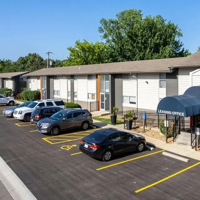 Aerial view of a residential apartment complex with multiple buildings, parking spaces, and a learning office entrance.