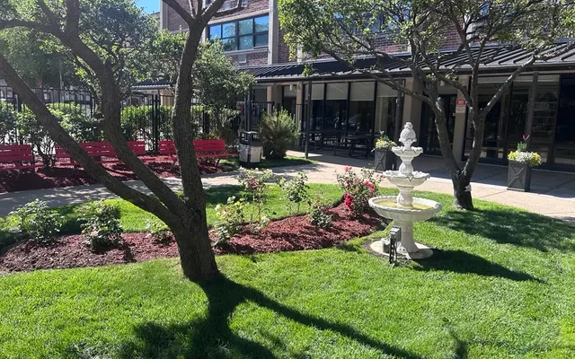 Community Garden Oasis A view of a landscaped outdoor garden area featuring a fountain, flowers, and seating.