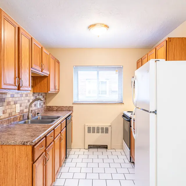 Cozy Kitchen Interior A kitchen featuring wooden cabinets and modern appliances, with a window providing natural light.