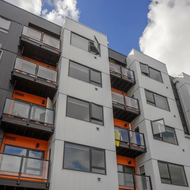 Modern Apartment Building A modern apartment building with a blend of grey and white panels and orange accents on the balconies.