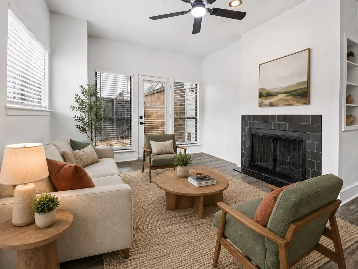 Cozy Modern Living Room A cozy modern living room featuring a light-colored sofa, two armchairs, a round coffee table, and a fireplace. Large windows provide natural light, and a plant adds a touch of greenery.