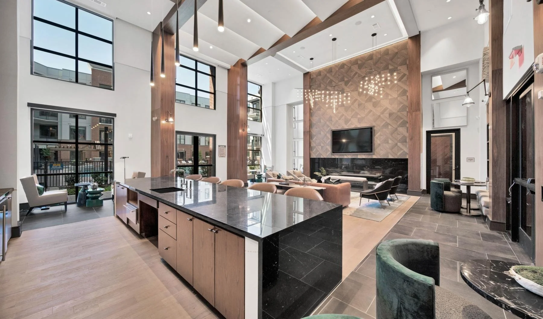 A spacious modern living area featuring large windows, a high ceiling, a fireplace, and stylish furniture.