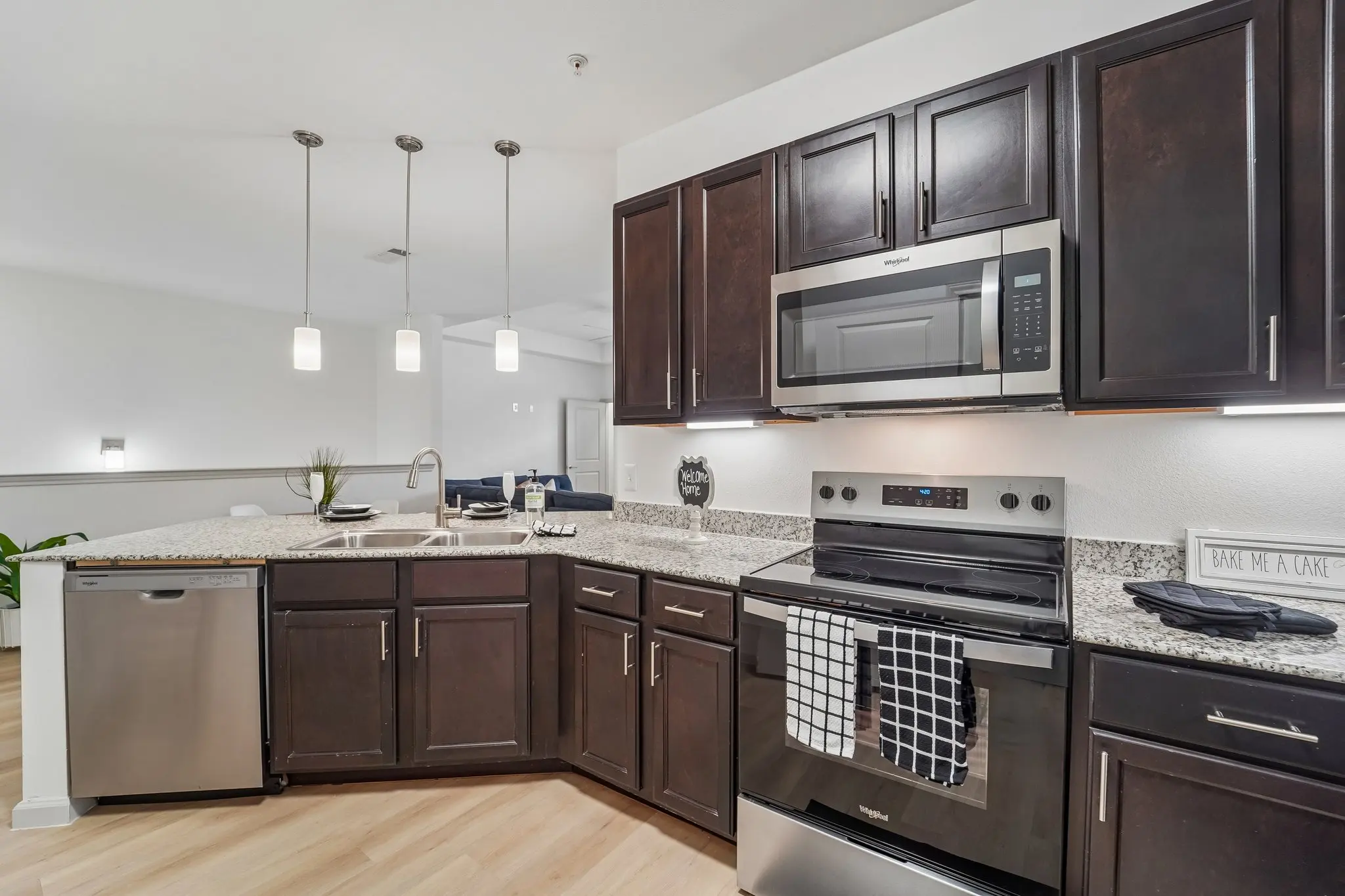A modern kitchen featuring dark wooden cabinets, stainless steel appliances, and a granite countertop with bar seating.