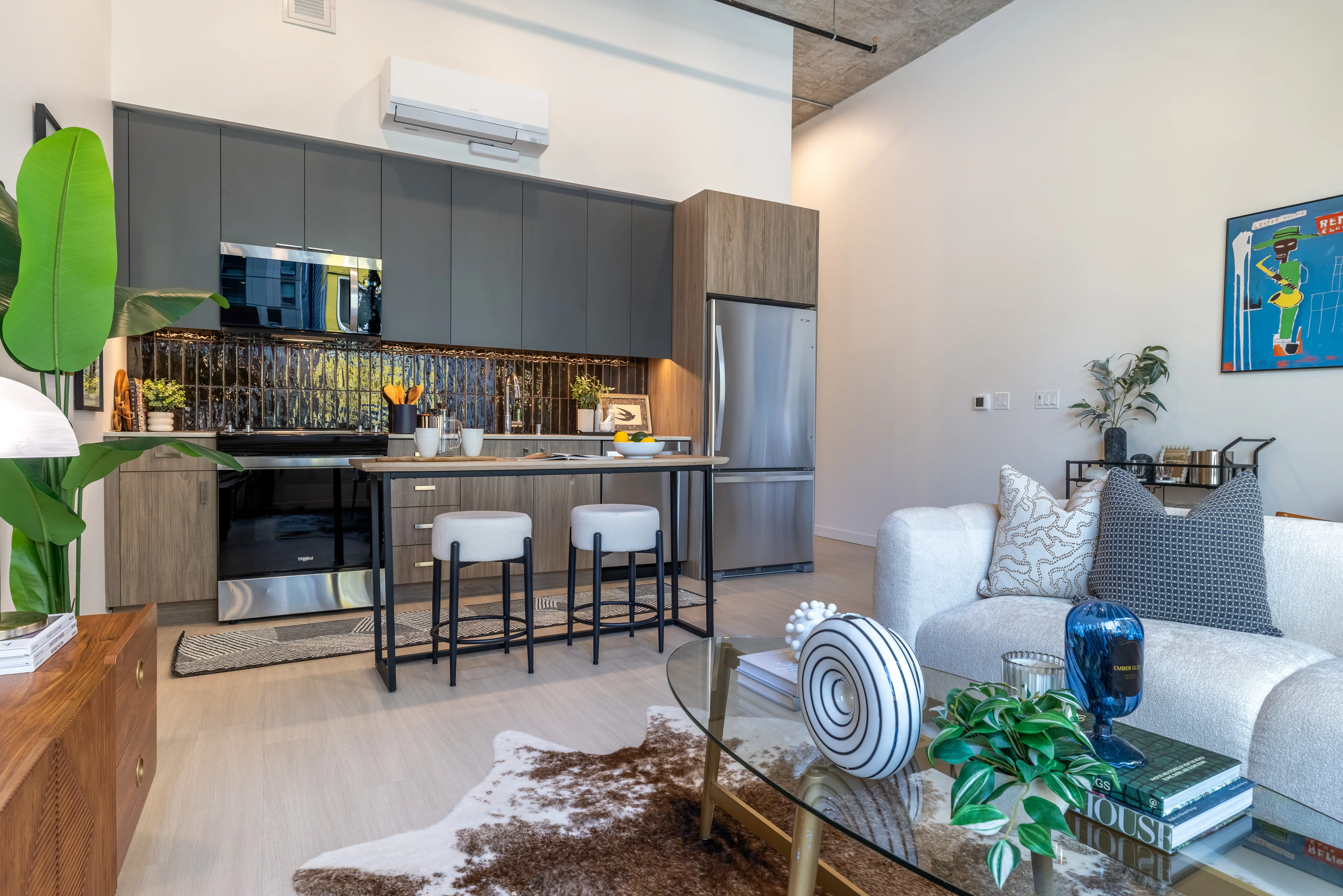 Stylish Modern Living Space A modern kitchen and living room setup featuring a cozy sofa, a stylish coffee table, and an open kitchen with sleek cabinetry and stainless steel appliances.