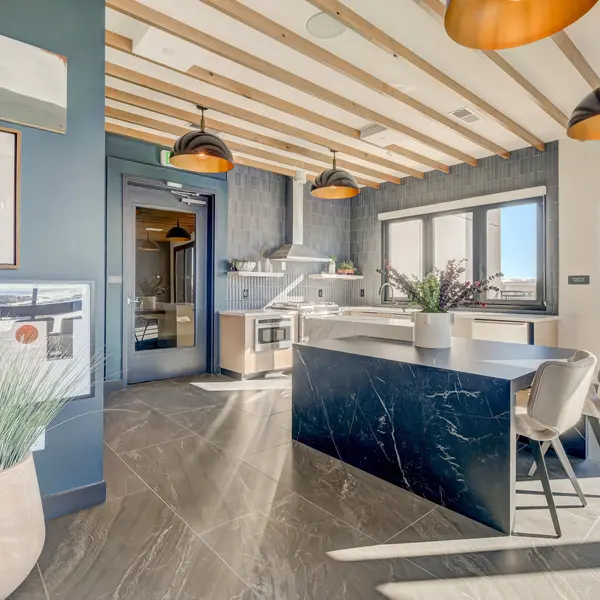 Modern kitchen with dark cabinetry, an island, pendant lights, and large windows, featuring stylish decor and a spacious layout.