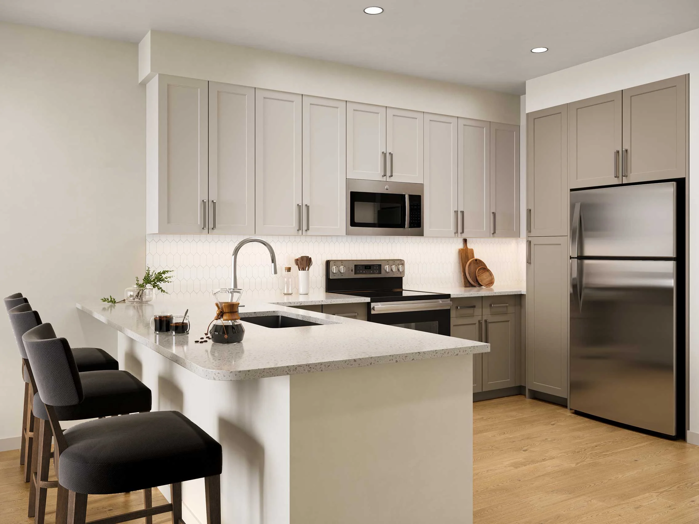 A modern kitchen featuring light gray cabinetry, stainless steel appliances, and a large island with bar stools.