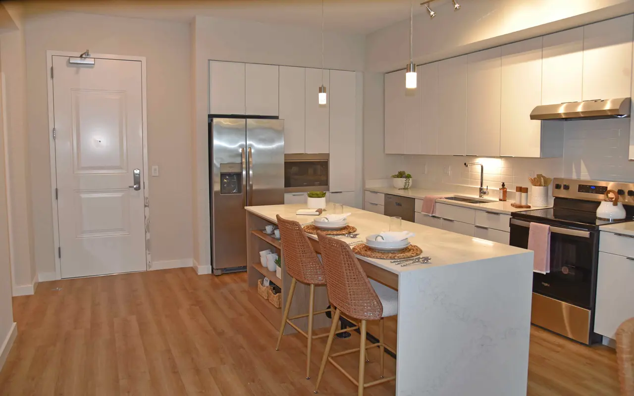 A modern kitchen featuring a spacious layout with white cabinets, stainless steel appliances, and a large island with seating.