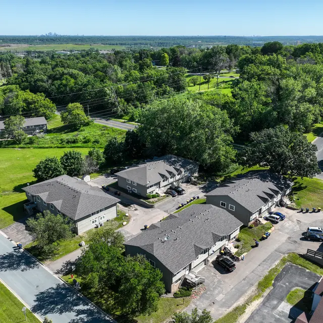 Court Place - Aerial View Aerial view of a residential area showcasing several buildings surrounded by greenery and trees, with a curved road leading through the neighborhood.