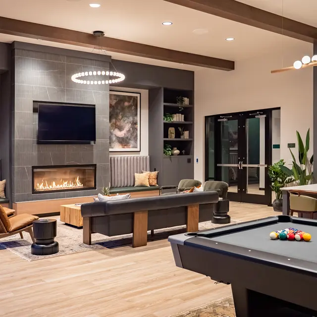 A stylish lounge area featuring a pool table, a fireplace, and contemporary seating arrangements.
