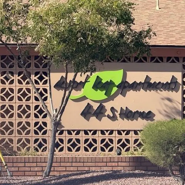 Desert Apartments Sign Sign for Desert Apartments featuring stylized text and green leaf designs on a textured wall.