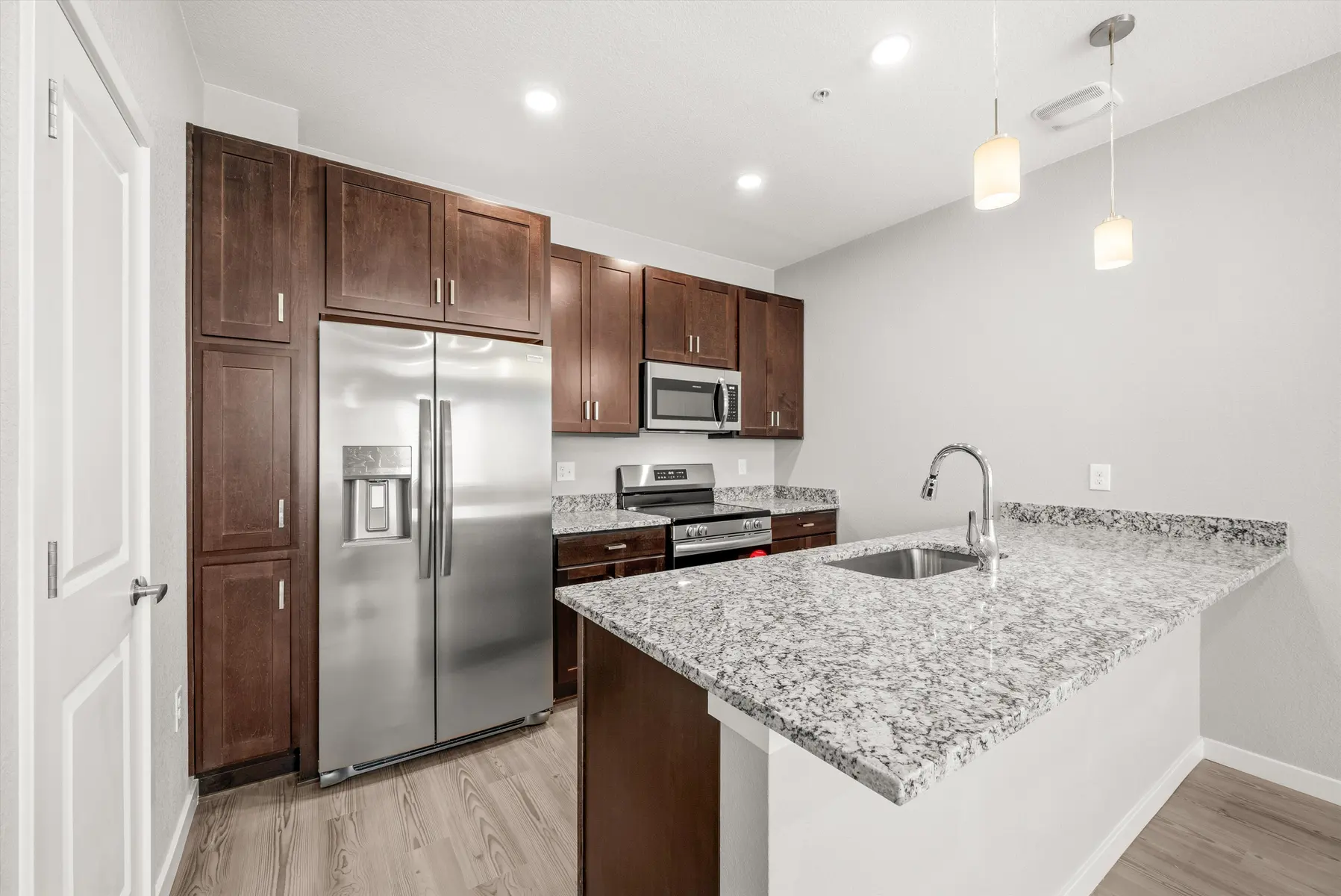 Modern Kitchen Design Contemporary kitchen featuring dark wood cabinets, stainless steel appliances, and a granite countertop island.