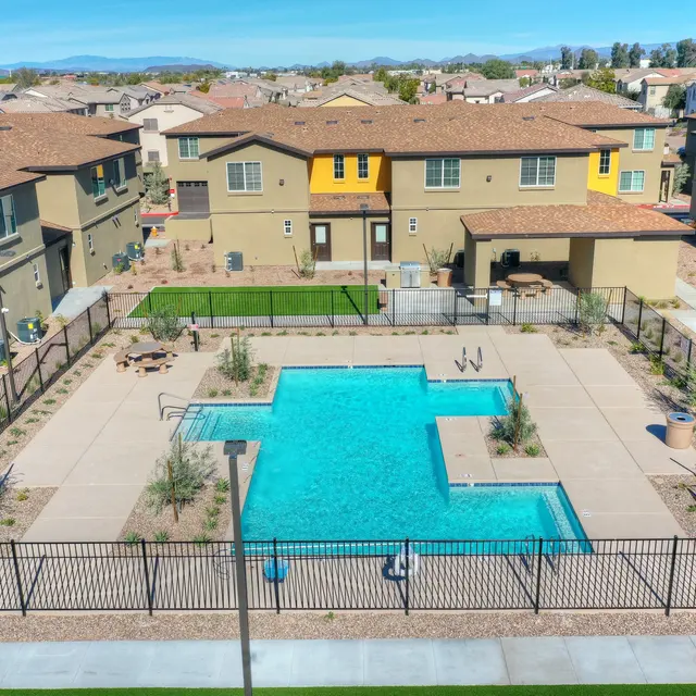 Community Pool Area An aerial view of a community pool surrounded by homes in a residential area, featuring lounge chairs and a grassy area.