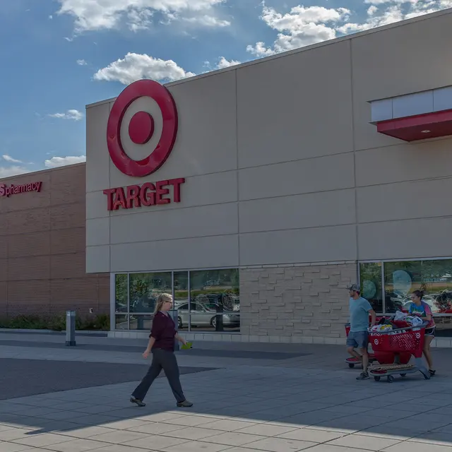 Exterior view of a Target store with shopping carts outside and two people walking by.
