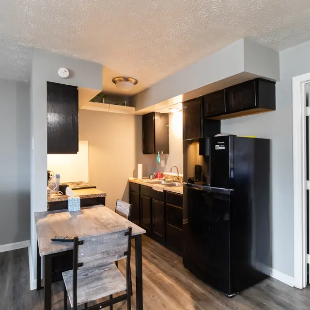 Compact kitchen and dining area featuring wooden table and black appliance set.