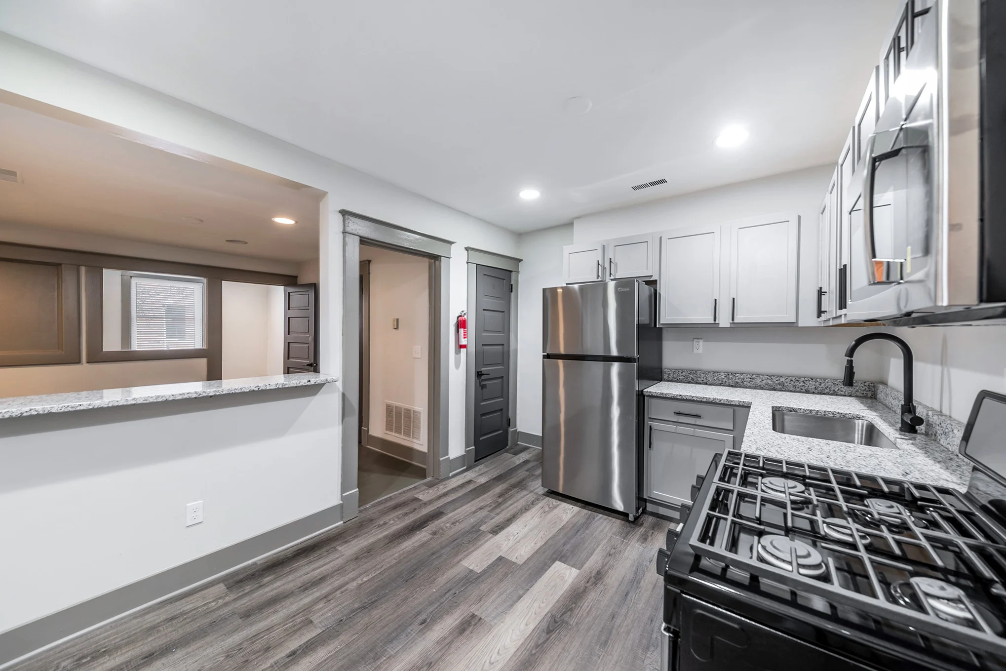 A modern kitchen featuring stainless steel appliances, granite countertops, and a spacious layout with a view of the adjacent room.