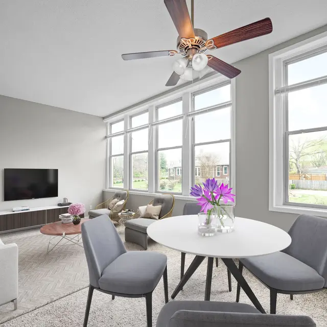 A light and airy modern living room featuring a sofa, dining table, and large windows with natural light.