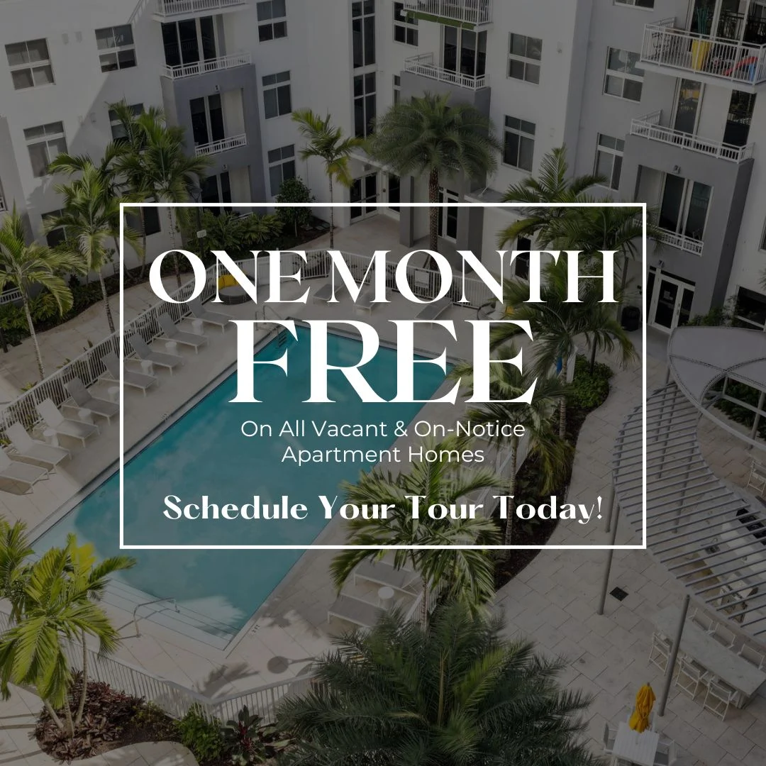 Aerial view of an apartment complex featuring a swimming pool surrounded by palm trees.