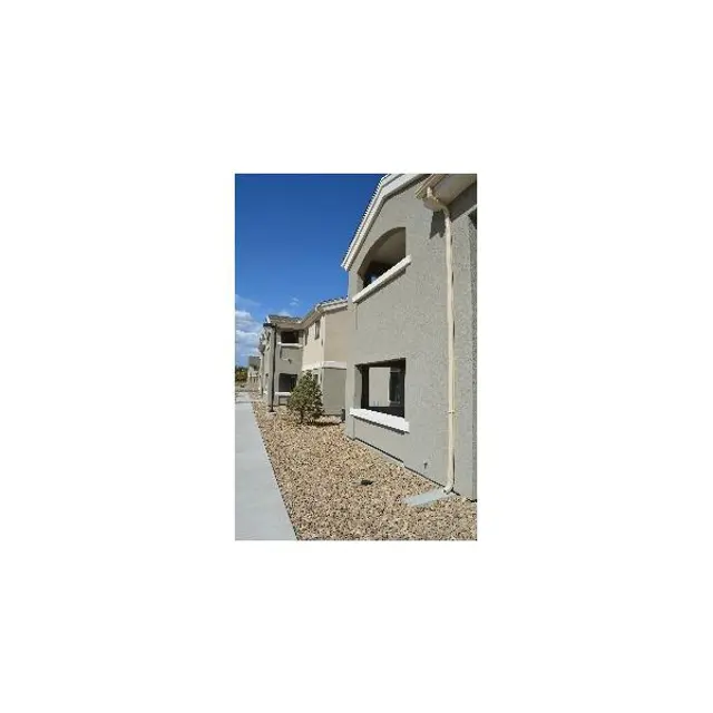 Exterior view of a residential building with a clear blue sky and a gravel pathway.