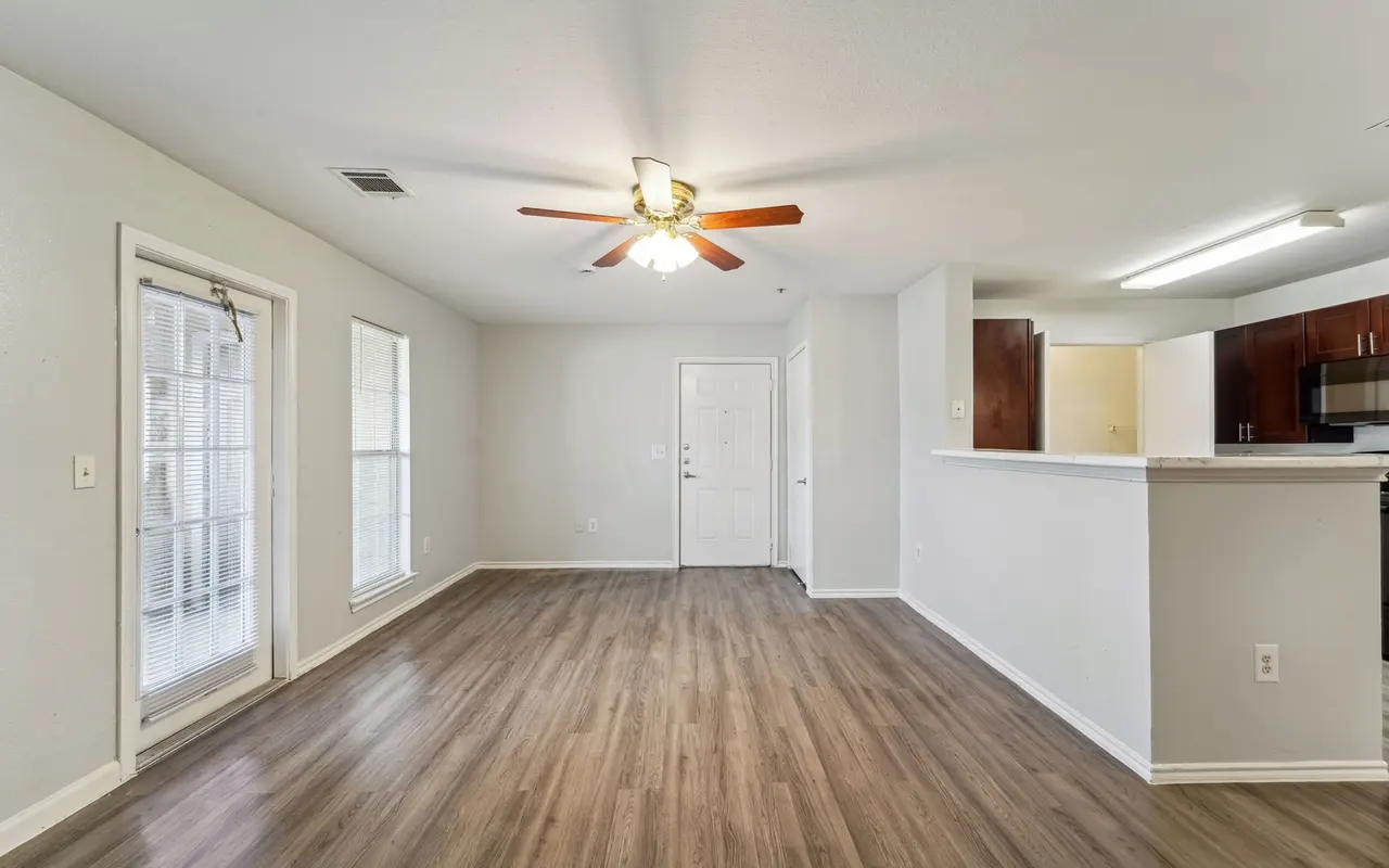 Spacious living room featuring a ceiling fan, hardwood flooring, and multiple windows allowing natural light.
