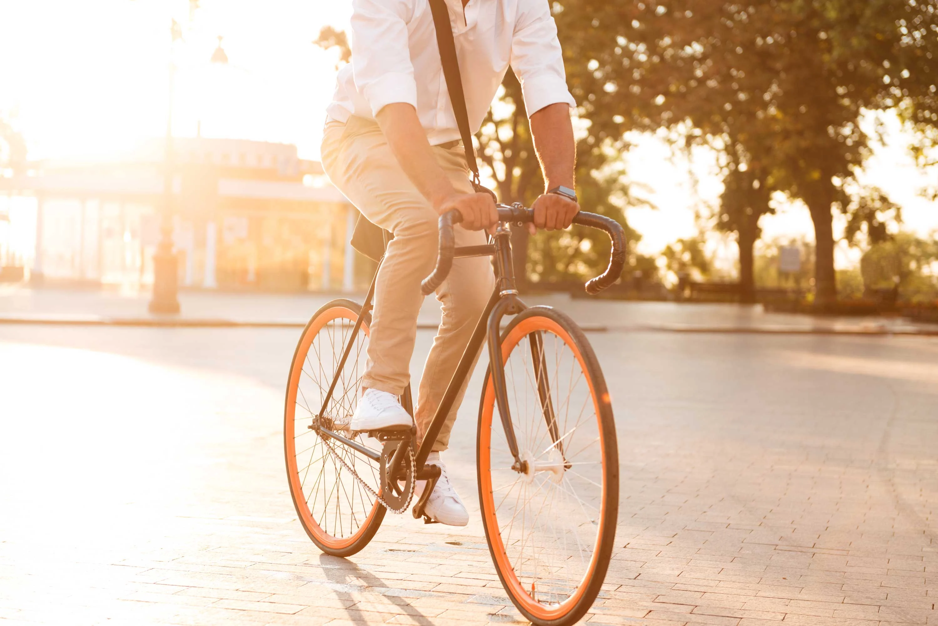 Cyclist in the Sun A person riding a bicycle on a sunny day, wearing light-colored clothing, with an urban setting in the background.