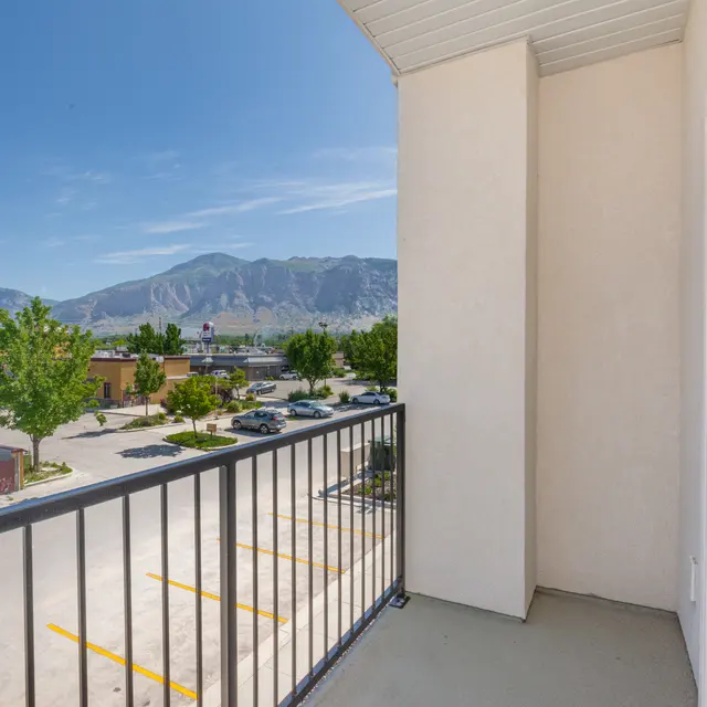 A view from a hotel balcony overlooking a parking lot and a mountainous landscape in the background.