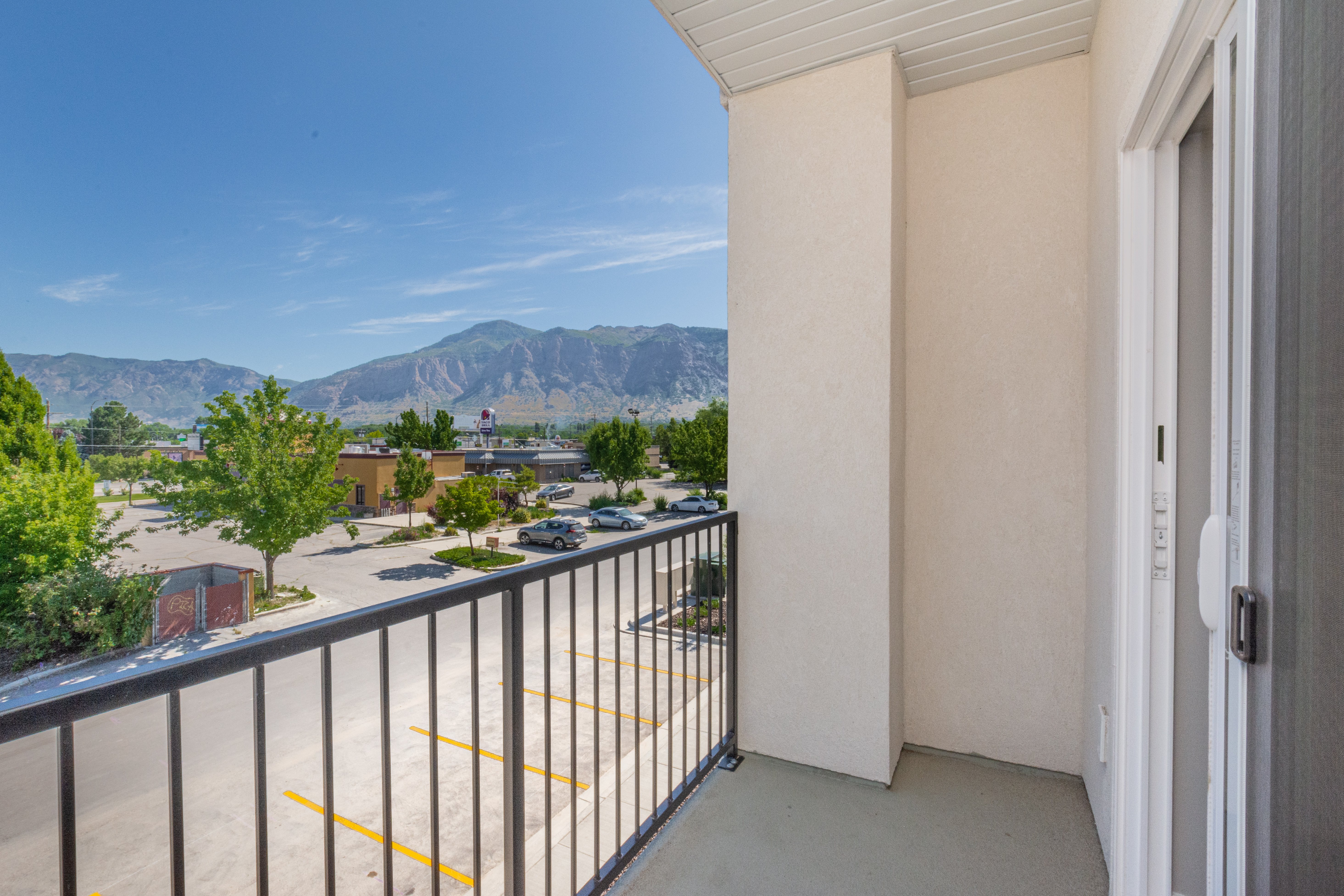A view from a hotel balcony overlooking a parking lot and a mountainous landscape in the background.