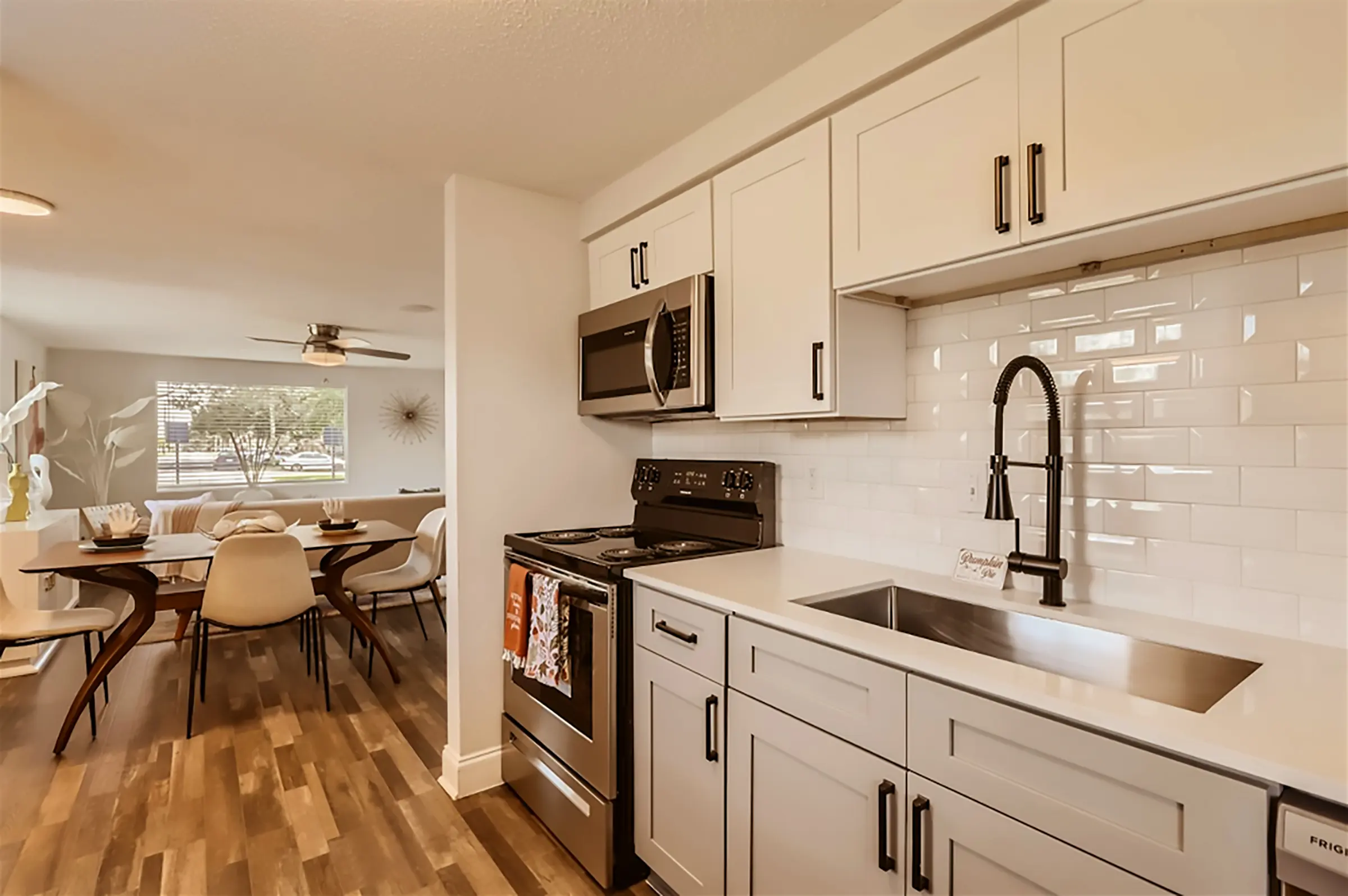 Stylish Modern Kitchen A modern kitchen featuring sleek cabinetry, stainless steel appliances, and a large sink. The adjacent dining area includes a round table with stylish chairs.