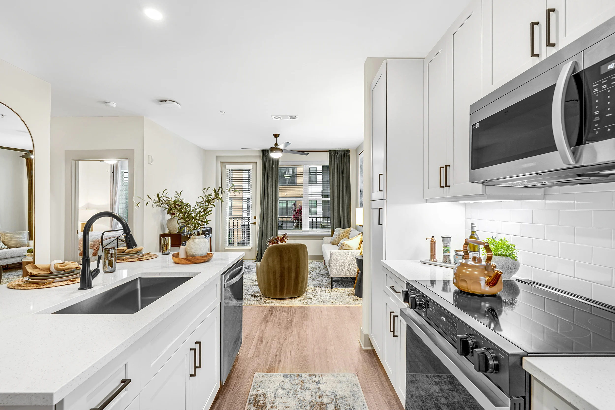Modern Kitchen and Living Space A view of a modern kitchen with white cabinets and a gray countertop, leading into a cozy living area with natural light.