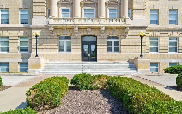 Historic Building Facade A view of a large brick building featuring ornate architectural elements, wide steps leading to a central door, and manicured landscaping in the foreground.