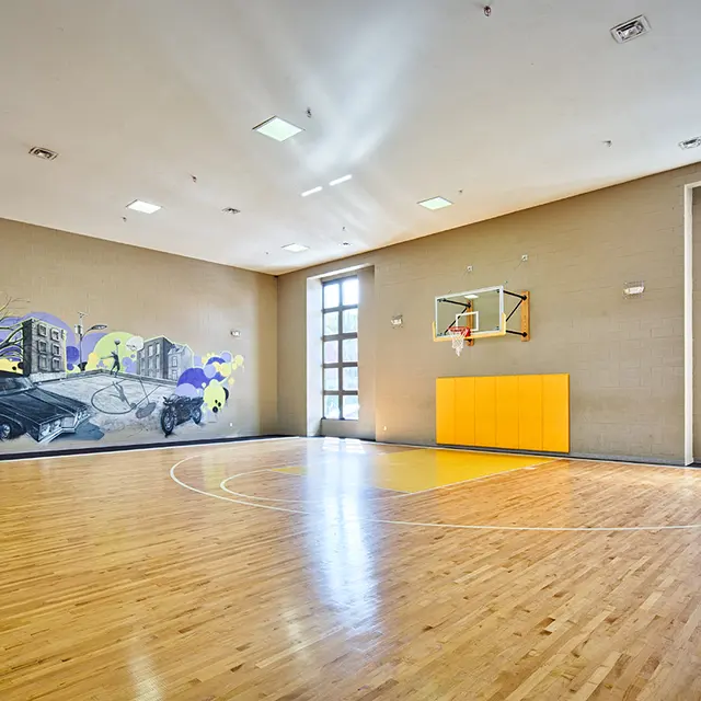 Interior of a basketball court featuring wooden flooring and a mural on the wall.