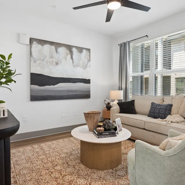 Chic Modern Living Room A bright and airy living room featuring a beige sofa, round coffee table, and decorative plants, with large windows letting in natural light.