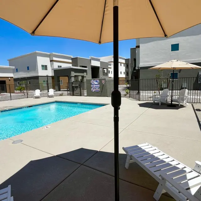 Relaxing Poolside Retreat A sunny pool area featuring a swimming pool with lounge chairs and umbrellas.