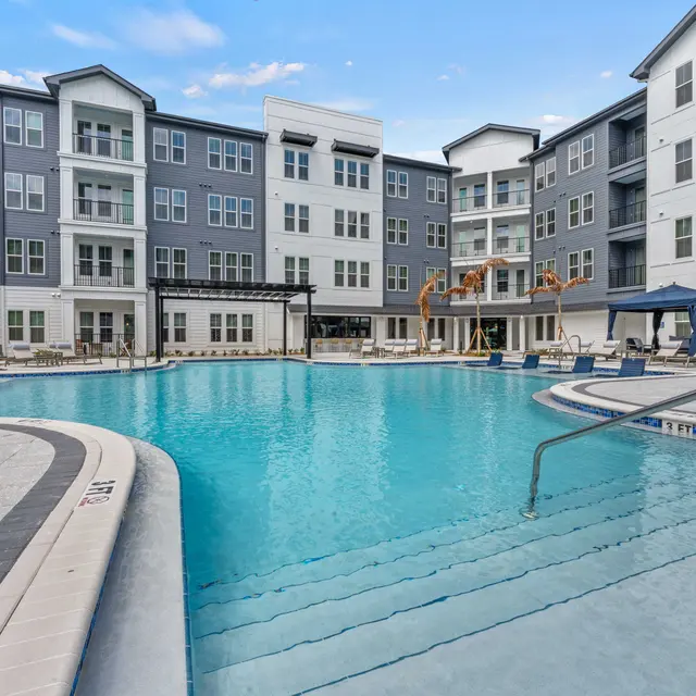 Modern Apartment Pool Area A bright outdoor swimming pool surrounded by modern apartment buildings, featuring lounge chairs and a gazebo.