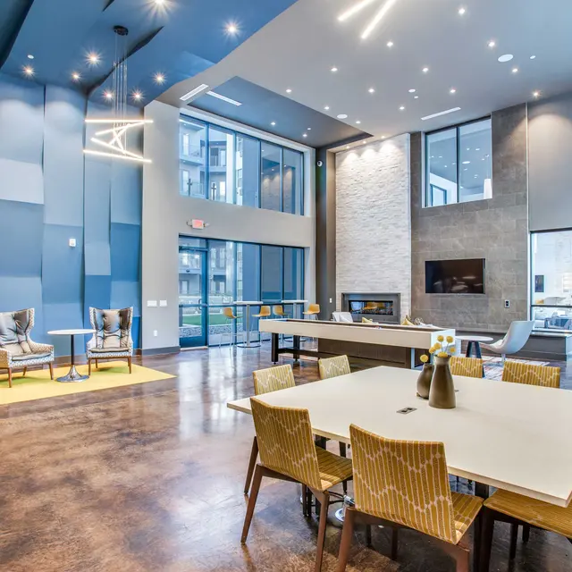 A spacious modern lounge area featuring blue accent walls, stylish furniture, and large windows letting in natural light.
