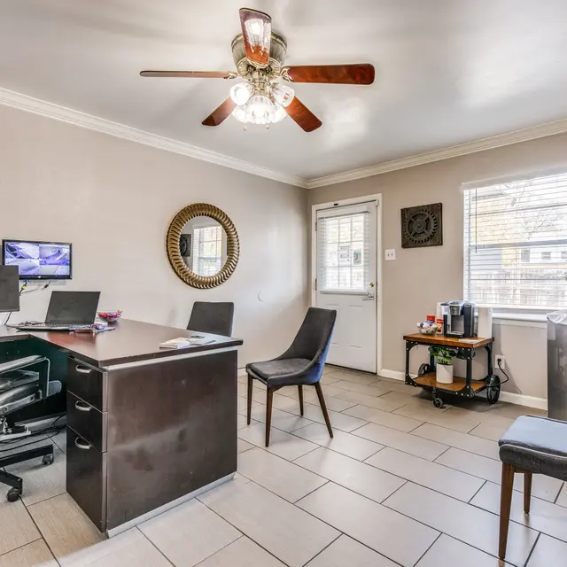 Cozy Home Office Setup A modern home office featuring a desk with computers, chairs, a wall clock, and a Christmas tree in the corner.