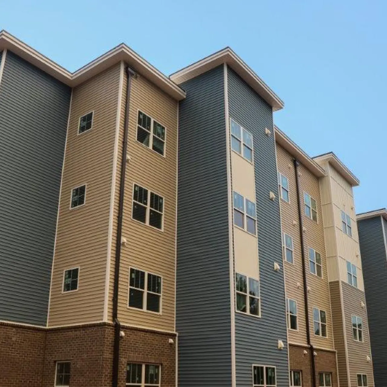 Modern multi-story apartment building featuring a mix of siding colors including beige and blue-gray.
