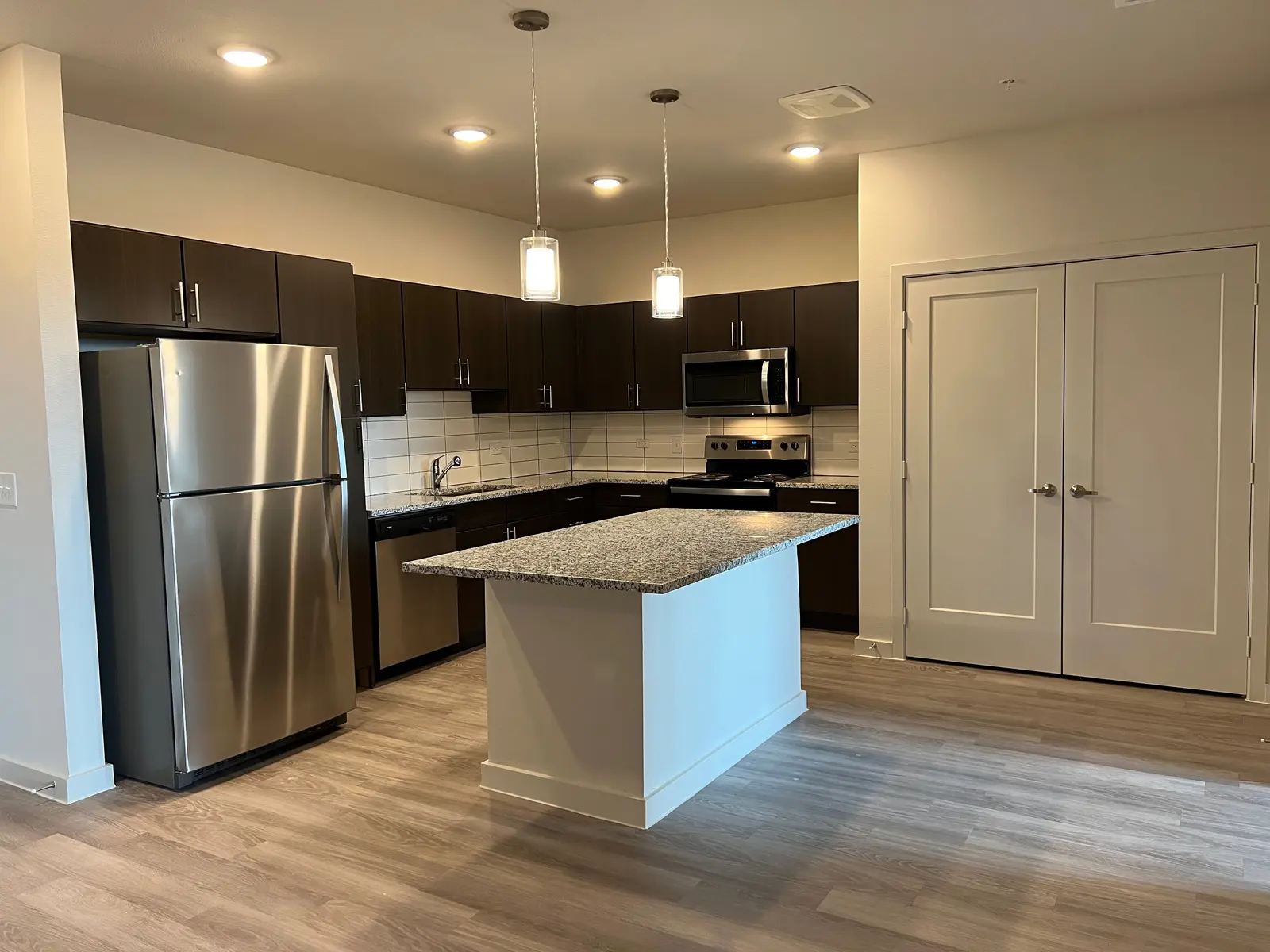 A modern kitchen with dark cabinetry, stainless steel appliances, and a spacious center island.
