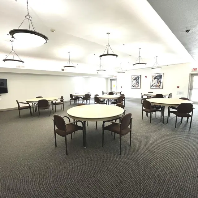 Spacious Community Room Bright and spacious community room with round tables and chairs.