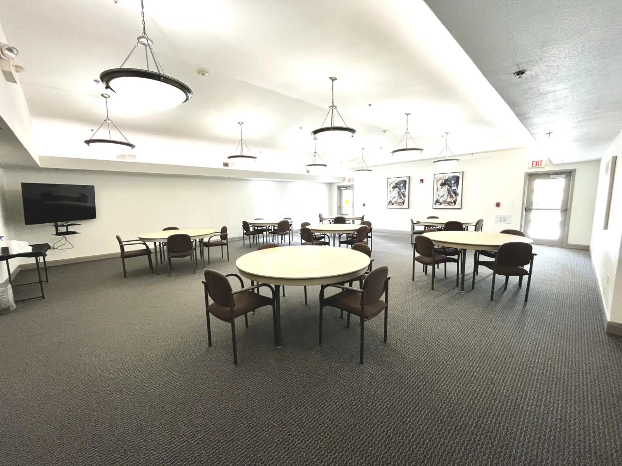 Community room with round tables,chairs and wall-mounted television.