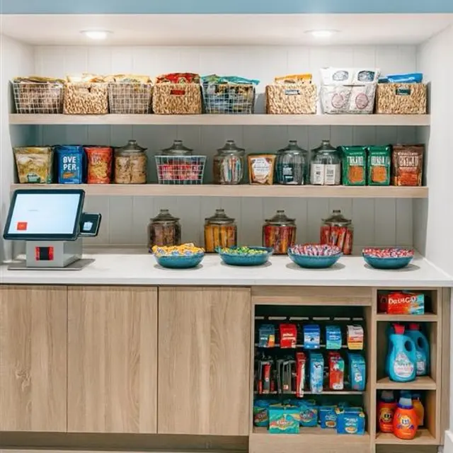 A well-organized snack bar displaying various containers of snacks and a checkout kiosk.