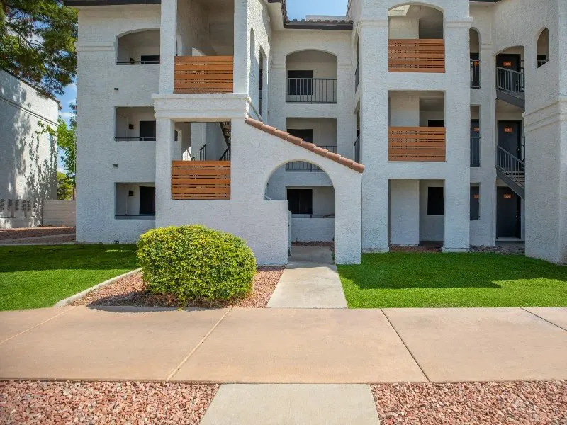 Front View of Apartment Complex Front view of a multi-story apartment complex with balconies, grassy areas, and a walkway.