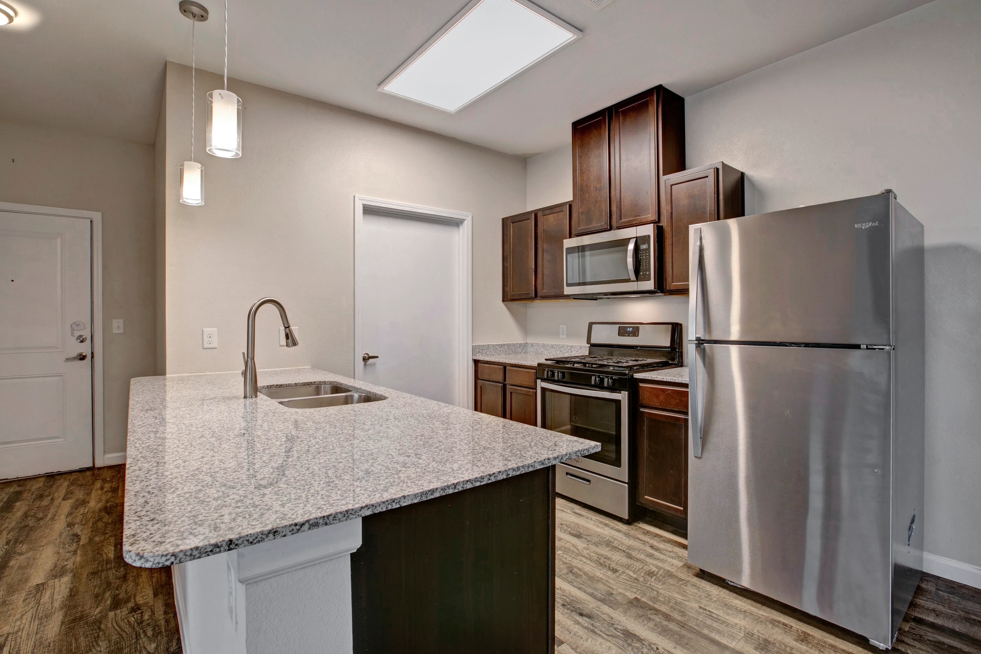 A modern kitchen featuring dark wood cabinets, stainless steel appliances, and a spacious countertop.