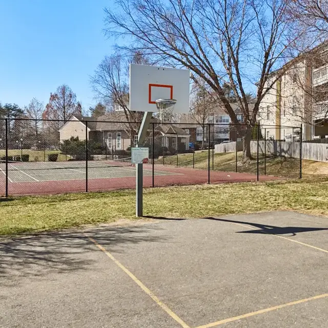 Outdoor basketball court with hoop and nearby tennis court