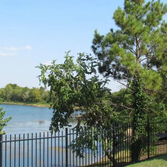A serene lake view with trees along the bank and an apartment building in the background.