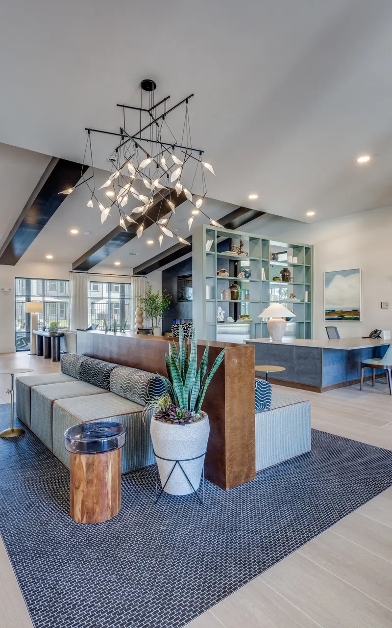 Contemporary Lobby Interior A spacious, modern lobby featuring a seating area with a long sofa and decorative plants, stylish lighting, and large windows letting in natural light.