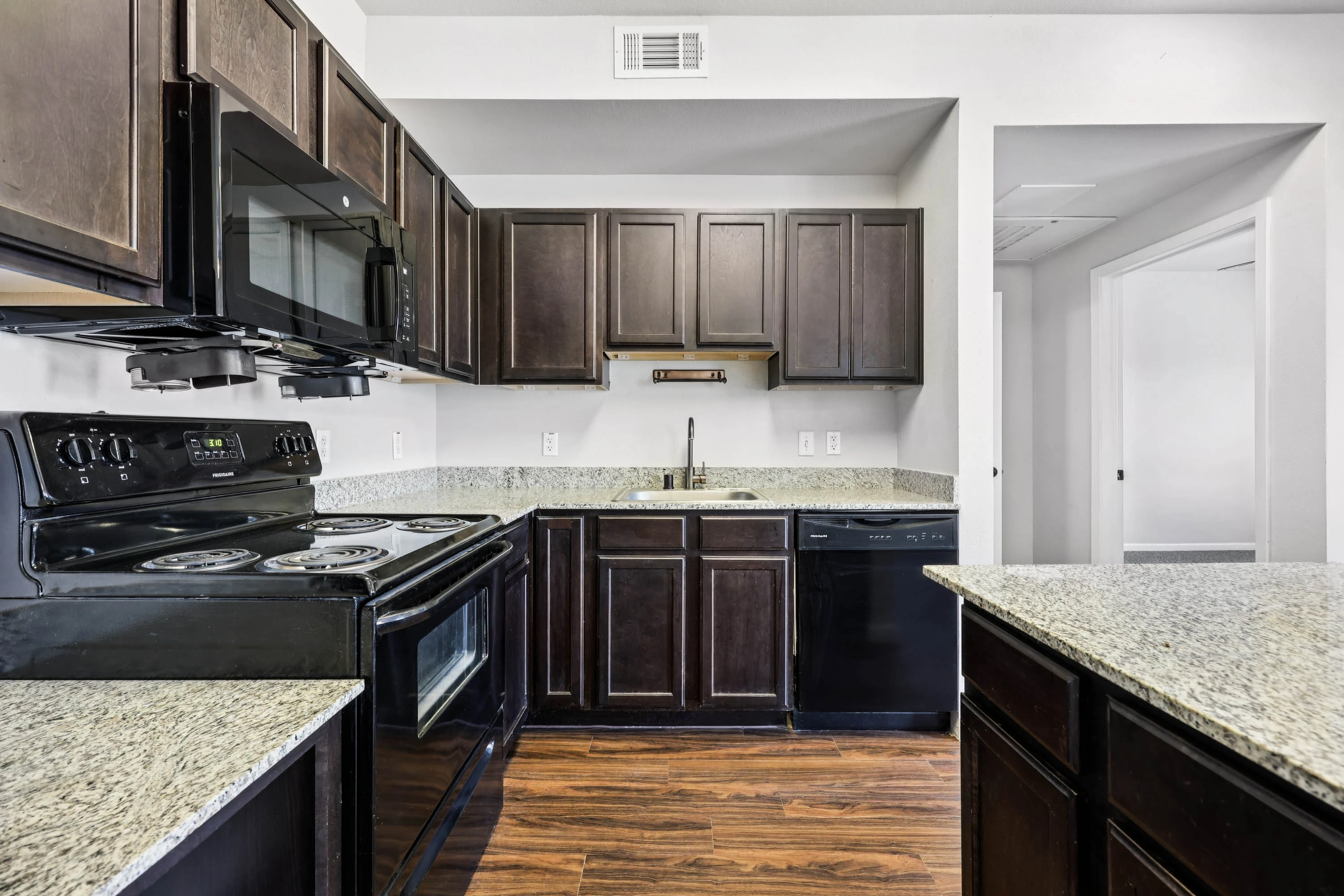Modern Kitchen Design A modern kitchen featuring dark wooden cabinets, black appliances, and a granite countertop.