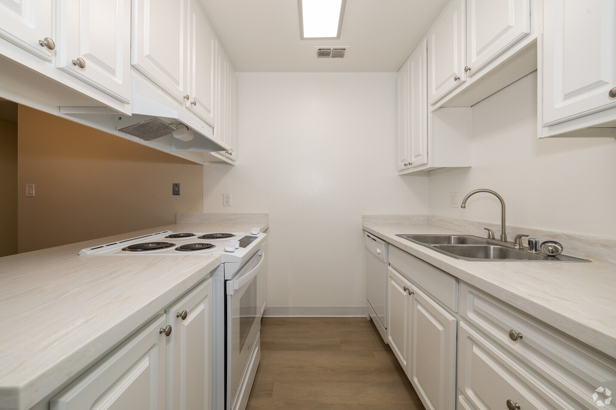 Modern Kitchen Interior A modern kitchen featuring white cabinetry, a countertop with a stove, and a double sink, with minimalistic design and natural wood flooring.