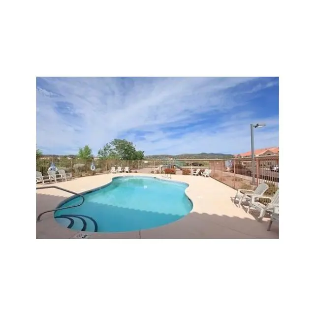 Refreshing Swimming Pool Area A clear swimming pool surrounded by a patio area with lounge chairs, under a blue sky with wispy clouds.