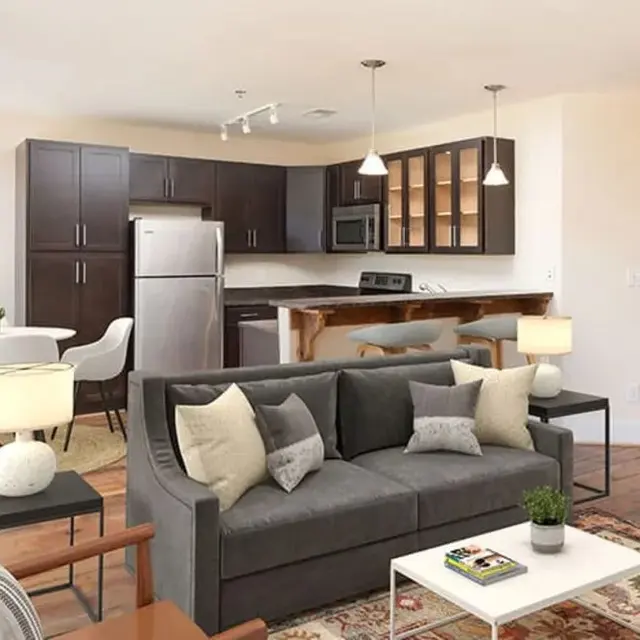 A modern living room with a sofa, coffee table, and kitchen area in the background.