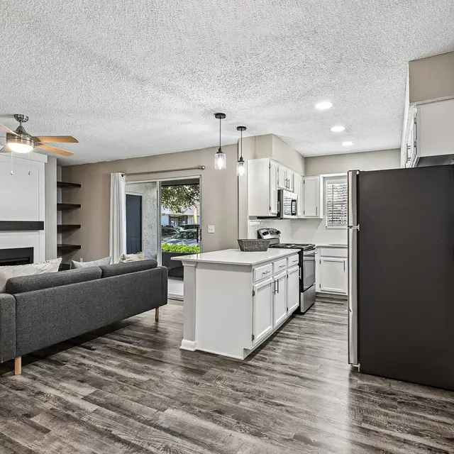 Contemporary Kitchen and Living Room A modern kitchen and living room area featuring a sofa, white cabinets, and stainless steel appliances.